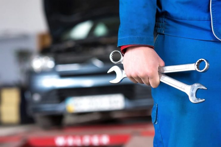 Car mechanic holding spanners