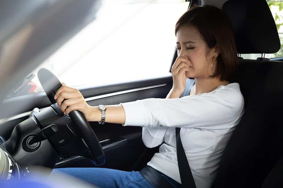 woman smelling a bad smell in a car