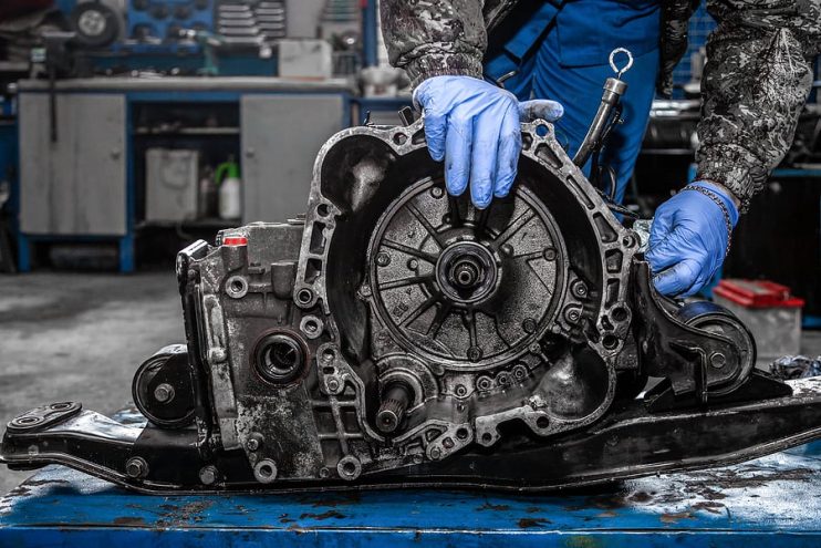 man repairing vehicle transmission