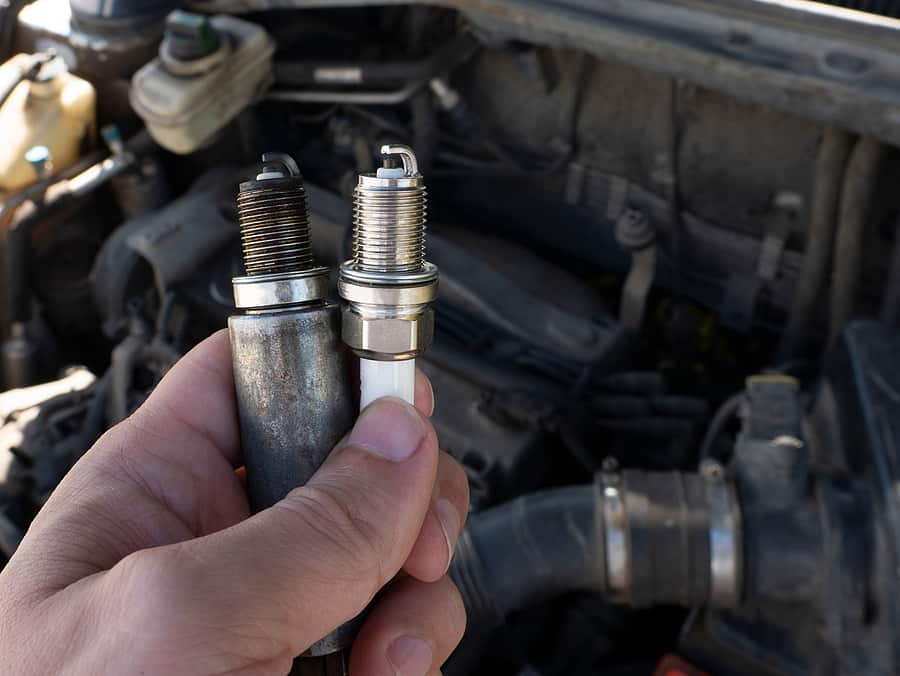 Man Holding old and new car spark plugs 