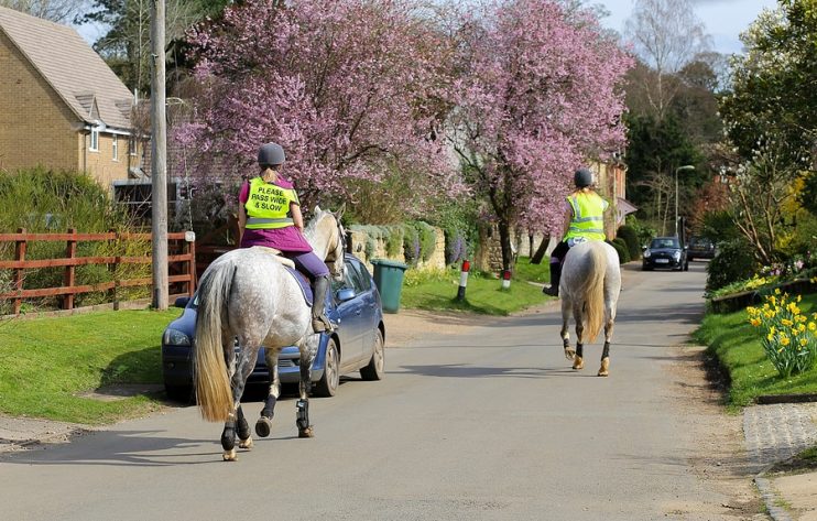 horses riding on a village road