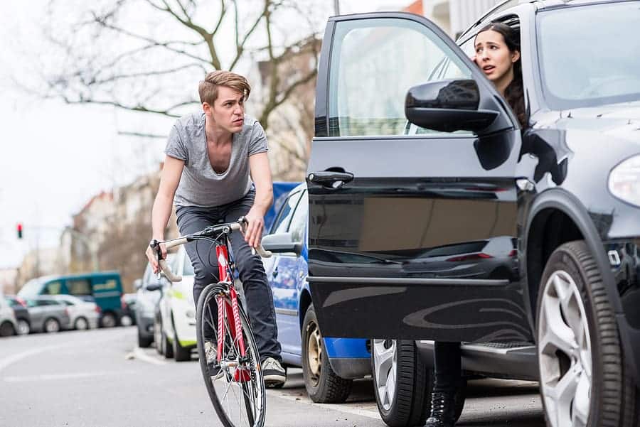 opening a car door in front of a cyclist