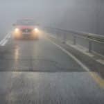 Fog On The Road In The Mountains.a Car Drives Through The Fog Wi