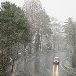 A Country Road And Forest During A Snowstorm With Heavy Winds An