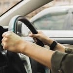 Female Hands On The Steering Wheel Of A Car While Driving On The