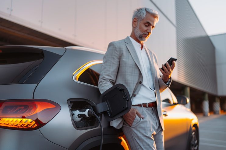 businessman waiting for electric vehicle to charge up